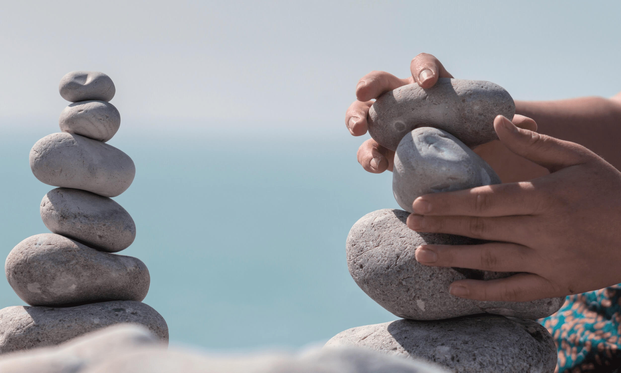 Steine sorgfältig übereinander gestapelt am Strand, symbolisierend Balance und Achtsamkeit.